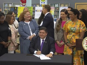 In this screenshot from a livestream broadcast by the State of Illinois, Gov. J.B. Pritzker signs a bill, Monday, June 12, 2023, at Harold Washington Library's Thomas Hughes Children's Library in downtown Chicago.