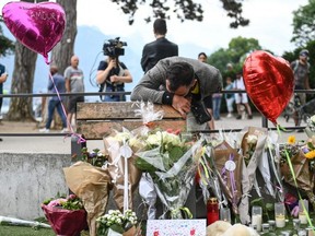 A man reacts in front of flowers and candles for the victims of a stabbing attack that occurred the day before in a park in Annecy, France, Friday, June 9, 2023.