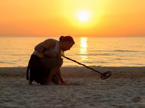 Man use metal detector on the beach in sun set