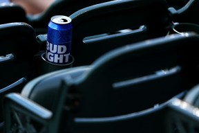 A tall can of Bud Light sits in cup holder in stadium.