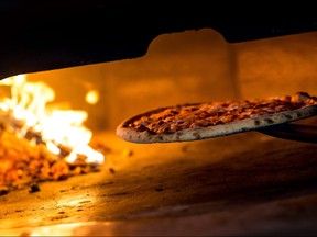 A pizza is removed from a wood burning oven in a classic Italian restaurant