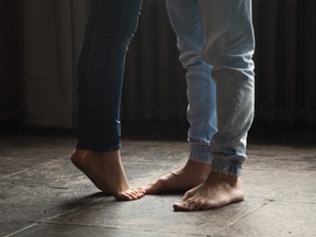 Girl standing on tiptoe to kiss man, couple feet closeup