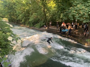 Surfers on the Eisbach river, gateway to the Englischer Garten city park.