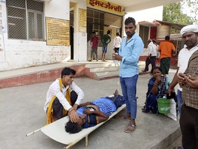 Relatives attend to a patient lying on a stretcher during a heat wave