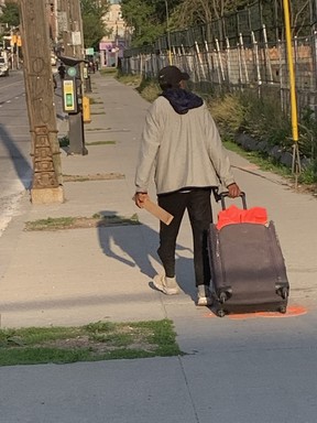 Man walks with suitcase and a piece of wood which he was often swinging in the direction of people he came in contact with -- Joe Warmington photo