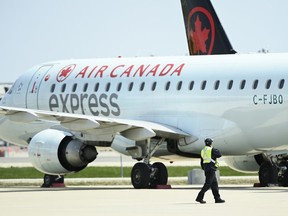 Airline ground crew walks past grounded Air Canada planes as they sit on the tarmac at Pearson International Airport In Toronto on Tuesday, April 27, 2021.