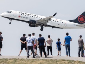 People look on as an Air Canada plane takes off.