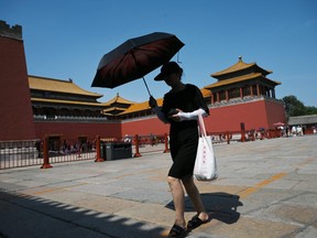 A woman shelters from the sun under an umbrella as she visits the Forbidden City