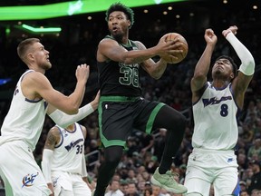 FILE - Boston Celtics guard Marcus Smart, center, looks to pass past Washington Wizards center Kristaps Porzingis, left, and forward Rui Hachimura, right, during the first half of an NBA basketball game Oct. 30, 2022, in Boston. A person with knowledge of the deal says the Wizards have agreed to trade Porzingis to the Celtics. The person spoke to The Associated Press on condition of anonymity because the agreement hadn't been announced. The trade comes with Porzingis accepting his player option for next season. ESPN reports the deal also includes the Memphis Grizzlies who are acquiring Smart from Boston in exchange for first-round draft picks in 2023 and 2024.
