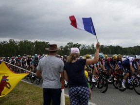 FILE - Spectators wave flags as the pack rides during the nineteenth stage of the Tour de France cycling race over 188.5 kilometers (117.3 miles) with start in Castelnau-Magnoac and finish in Cahors, France, Friday, July 22, 2022. The 110th edition of the Tour de France starting Saturday, July 1, 2023, from Bilbao, Spain.