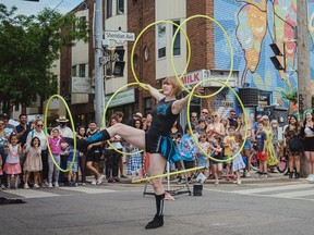 Hula-hoop acrobat performs on a street.