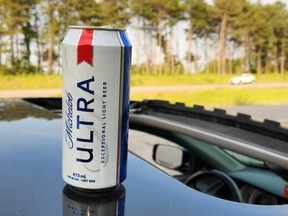 A beer can rests on top of a vehicle.