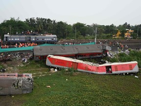 Railway workers help to restore services at the accident site in India