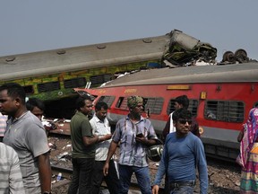 People inspect the site of passenger trains that derailed in Balasore district, in the eastern Indian state of Orissa, Saturday, June 3, 2023. Rescuers are wading through piles of debris and wreckage to pull out bodies and free people after two passenger trains derailed in India, killing more than 280 people and injuring hundreds as rail cars were flipped over and mangled in one of the country's deadliest train crashes in decades.