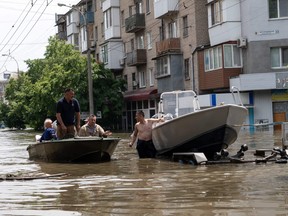 A local resident sets afloat his boat onto the water during an evacuation from a flooded area in Kherson