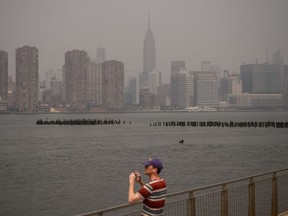 A man photographs the Manhattan city skyline during heavy smog