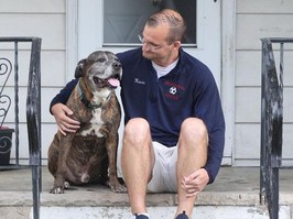 Happy dog sitting on porch with owner.