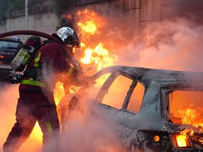 A firefighter works to put out a burning car