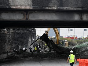 Workers inspect and clear debris from a collapsed bridge