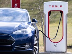 A Tesla Model S sedan is plugged into a Tesla Supercharger electrical vehicle charging station