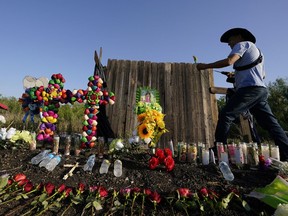 Roberto Marquez adds a flower to a makeshift memorial