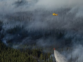 The Donnie Creek wildfire burns as a helicopter dumps water in an area between Fort Nelson and Fort St. John, B.C. in this undated handout photo provided by the BC Wildfire Service.