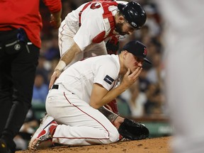Boston Red Sox starting pitcher Tanner Houck kneels on the mound, bleeding after being struck on the cheek by a line drive by of New York Yankees' Kyle Higashioka during the fifth inning of a baseball game Friday, June 16, 2023, at Fenway Park in Boston.