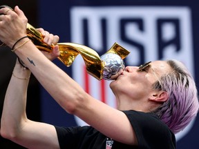 USA women's soccer player Megan Rapinoe kisses the women's World Cup trophy.