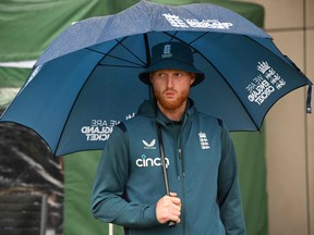England captain Ben Stokes shelters under an umbrella after the game is abandoned without any play on day five of the fourth Ashes cricket Test match.