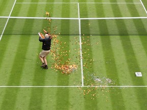 A protester is challenged by security on court 18 after a Just Stop Oil protest using orange confetti and a jigsaw puzzle during the Women's Singles first round match between Katie Boulter of Great Britain and Daria Saville of Australia during day three of The Championships Wimbledon 2023 at All England Lawn Tennis and Croquet Club on July 05, 2023 in London, England.