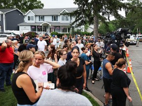 People watch as law enforcement officials investigate the home of a suspect arrested in the unsolved Gilgo Beach killings on July 14, 2023 in Massapequa Park, N.Y.
