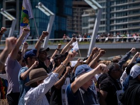 Striking port workers from the International Longshore and Warehouse Union Canada hold up their fists while attending a rally in Vancouver, on Sunday, July 9, 2023.