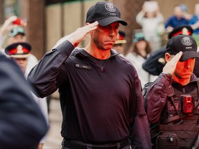 Toronto Police Sgt. Brandon Smith, wearing Bingo's tag, salutes as his K9 partner leaves Toronto for Guelph after being slain on the job.