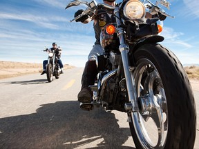 Two men riding motorcycles along road