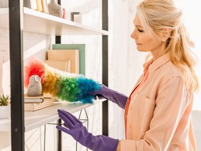 Senior woman in rubber gloves cleaning shelves with dusterSenior woman in rubber gloves cleaning shelves with duster