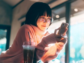 Young woman wearing glasses using mobile phone for dating app.