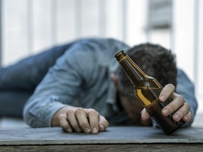 DRUNK MAN LYING ON THE FLOOR ASLEEP WITH A BOTTLE OF BEER IN HIS HAND