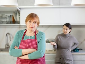 Elderly sad woman stands in kitchen and listens to insults.Concept stream of abuse
