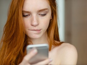 Closeup of beautiful redhead woman looking at smartphone.
