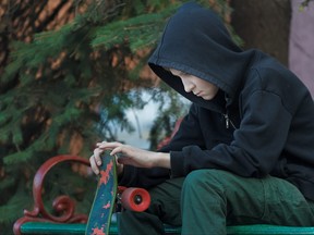 Portrait of relaxing teenager is looking at skateboard in his hands