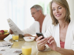 Couple in kitchen eating breakfast and reading newspaper