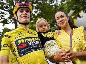 Jumbo-Visma's Danish rider Jonas Vingegaard wearing the overall leader's yellow jersey celebrates victory with his wife Trine Hansen and their daughter at the end the 21st and final stage