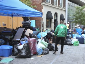 Asylum seekers with all of their worldly possessions continued to sleep on the street outside of the City of Toronto shelter on Peter St. as they waited for housing on Friday, July 14, 2023.