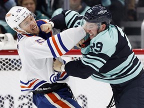 Vince Dunn of the Seattle Kraken, right, fights Dylan Holloway of the Edmonton Oilers