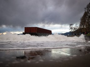 Waves crash into the seawall as a barge that drifted loose on English Bay sits grounded on rocks during a massive windstorm, in Vancouver, on Monday, November 15, 2021.