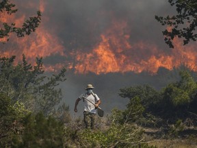 Flames burn a forest in Vati village