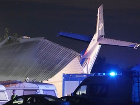 The tail of a Cessna 208 plane sticks out of a hangar after it crashed there in bad weather killing several people and injuring others, at a sky-diving centre in Chrcynno