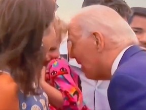 U.S. President Joe Biden leaning into little girl being held by mom.