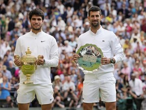 Spain's Carlos Alcaraz, left, celebrates with the trophy after beating Serbia's Novak Djokovic, right, to win the final of the men's singles on day fourteen of the Wimbledon tennis championships in London, Sunday, July 16, 2023.