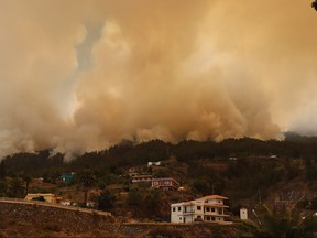 A picture taken on July 15, 2023 on the Spanish Canary Island of La Palma shows the evacuated town of Tijarafe surrounded by smoke
